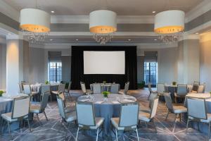 une salle de conférence avec des tables et des chaises et un écran de projection dans l'établissement Kimpton Hotel Palomar Philadelphia, an IHG Hotel, à Philadelphie