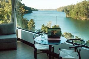 een laptop op een tafel in een kamer met uitzicht op een rivier bij Pura Lodge in Concepción