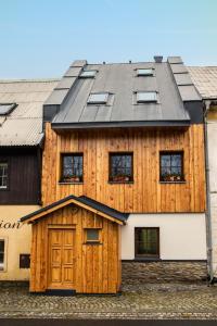 ein Holzhaus mit schwarzem Dach in der Unterkunft Apartmány Kůlna in Boží Dar