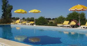 um grupo de cadeiras amarelas e guarda-sóis ao lado de uma piscina em Monte Da Serralheira Agro Turismo em Évora