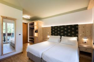 a bedroom with a large white bed in a room at Hotel Medil in Campitello di Fassa