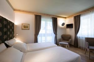 a hotel room with two beds and a window at Hotel Medil in Campitello di Fassa