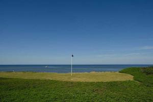 - un parcours de golf avec l'océan en arrière-plan dans l'établissement Duenenhof-zum-Kronprinzen-Appm-60, à Wenningstedt