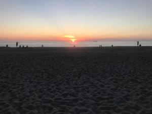 - un groupe de personnes sur une plage au coucher du soleil dans l'établissement Duenenhof-zum-Kronprinzen-Appm-60, à Wenningstedt