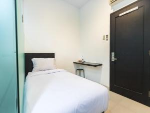 een slaapkamer met een wit bed en een zwarte deur bij Puri Maju Hotel in Jakarta