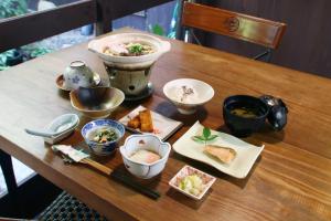 een houten tafel met kommen en borden met voedsel bij Ryoso Kawaguchi in Miyajima