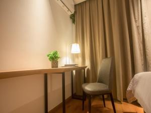 a room with a desk and a chair and a bed at GreenTree Inn Haikou Haixiu Middle Road in Haikou