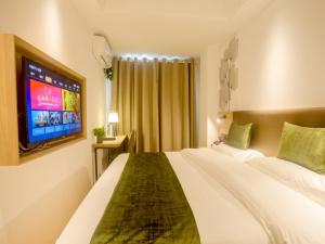 a hotel room with a large bed and a tv at GreenTree Inn Haikou Haixiu Middle Road in Haikou