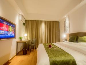 a hotel room with a large bed and a television at GreenTree Inn Haikou Haixiu Middle Road in Haikou