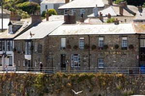 un vecchio edificio in pietra con la locanda stellata scritta sopra di The Ship Inn a Mousehole