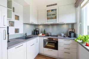 a white kitchen with white cabinets and a sink at Appartement-Leuchtturmblick in Hörnum