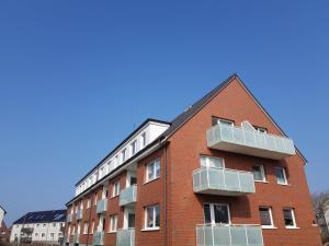 a red brick building with white balconies on it at Appartement-Leuchtturmblick in Hörnum