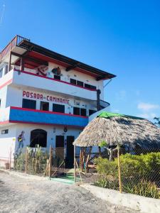 a white building with a balcony and a straw umbrella at Posada del Caminante in Puerto Villamil