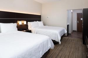 ein Hotelzimmer mit 2 Betten und einem Spiegel in der Unterkunft Holiday Inn Express & Suites - Romeoville - Joliet North, an IHG Hotel in Romeoville