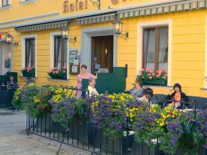 un gruppo di persone seduti fuori da un edificio giallo di Hotel-Garni Goldenes Kreuz a Grein