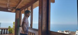 Un uomo in piedi su un balcone che guarda l'oceano di GOLVEN Surf a Taghazout