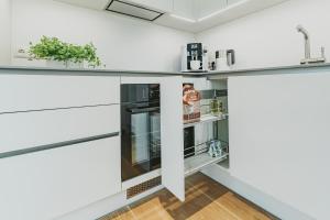 een keuken met witte kasten en een koelkast bij ÖÖ Street Premium Apartment with Terrace in Tartu