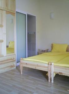 - une chambre dotée d'un lit avec des draps jaunes et un miroir dans l'établissement Guest House Antoaneta, à Nessebar