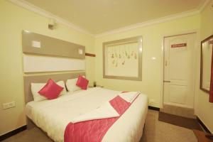 a bedroom with a large white bed with red pillows at Ganga's Sri Balaji Cottage in Ooty