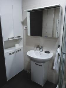 bagno bianco con lavandino e specchio di Apartment U 154 - Aparthotel Vučko a Jahorina