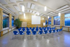 une salle de conférence avec des chaises bleues et un écran dans l'établissement Hotel am Schlossberg, à Herrenberg