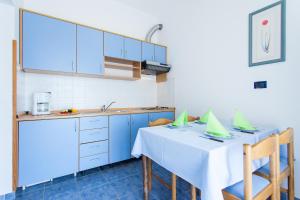 een keuken met blauwe kasten en een witte tafel en stoelen bij Apartments Villa Brioni II in Fažana