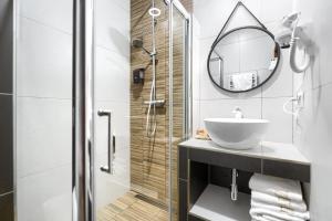 a bathroom with a sink and a shower with a mirror at Weranda Apartments in Morzyczyn