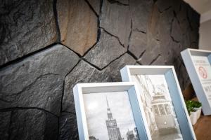 una pared de piedra con tres fotografías enmarcadas en ella en NEW Apartament GREEN Warszawa PARKING Free, en Wola Mrokowska