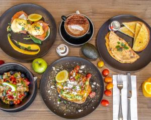 een tafel met borden ontbijtproducten en een kopje koffie bij Quest Bella Vista in Baulkham Hills