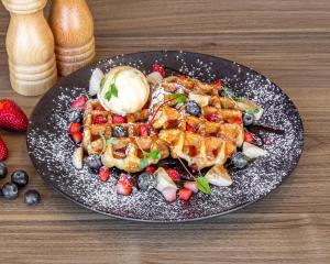 een bord met wafels en fruit op een tafel bij Quest Bella Vista in Baulkham Hills