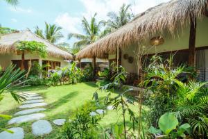 een huis met een grasdak en een tuin bij Mana Eco Retreat in Kuta Lombok