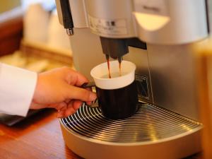 een persoon maakt een kopje koffie in een espressomachine bij Hotel Route-Inn Koriyama Minami in Koriyama