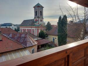 un grand bâtiment rose avec une tour d'horloge au-dessus des toits dans l'établissement Böne Vendégház és Borozó, à Tokaj