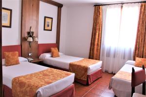 a hotel room with two beds and a window at Hotel El Bedel in Alcalá de Henares