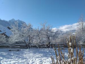 um parque coberto de neve com bancos e árvores em Le Bacchu Ber em Briançon