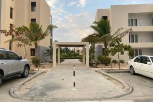 zwei Autos auf einem Parkplatz vor einem Gebäude geparkt in der Unterkunft Hawana Salalah lagoon beach apartment in Salalah