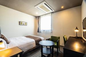 une chambre d'hôtel avec un lit, une table et des chaises dans l'établissement Hotel Quest Shimizu, à Shizuoka