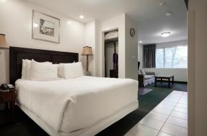 1 dormitorio con 1 cama blanca grande y sala de estar en The Business Inn, en Ottawa