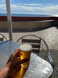 uma pessoa segurando um copo de cerveja numa mesa em Portugal Algarve Beach Apartment em Portimão