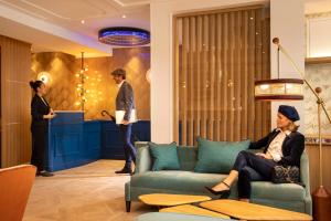 a woman sitting on a couch in a lobby at Hotel Phileas Lazare & Spa - Opera in Paris