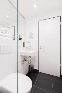 een witte badkamer met een toilet en een wastafel bij GuestHouse Speyer in Speyer