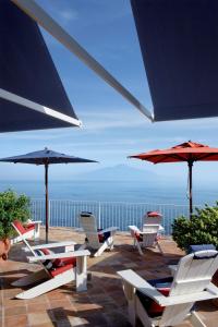 un gruppo di sedie e ombrelloni su un patio di Maison La Minervetta a Sorrento