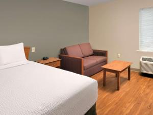 een hotelkamer met een bed en een stoel bij WoodSpring Suites Louisville Clarksville in Clarksville