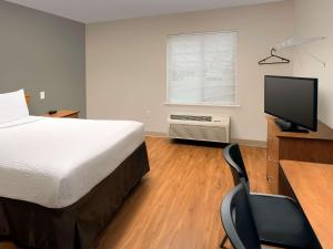 een slaapkamer met een bed en een bureau met een computer bij WoodSpring Suites Louisville Clarksville in Clarksville