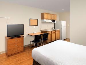 een slaapkamer met een bed en een bureau met een televisie bij WoodSpring Suites Louisville Clarksville in Clarksville