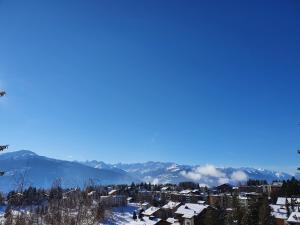 een stad in de sneeuw met bergen op de achtergrond bij Hôtel Splendide in Crans-Montana