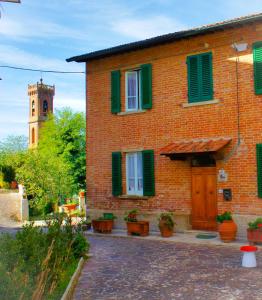 un edificio in mattoni con persiane verdi e una torre dell'orologio di Casa Fonte di Bacco a San Miniato