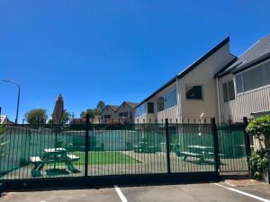 a fence with a picnic table in front of a building at Tui Oaks Motel in Taupo