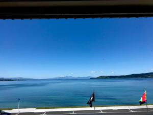 a view of a large body of water with two flags at Tui Oaks Motel in Taupo