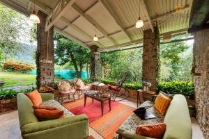 een afgeschermde veranda met een bank en stoelen bij SaffronStays Nandanvan Estate, Kodaikanal in Kodaikānāl